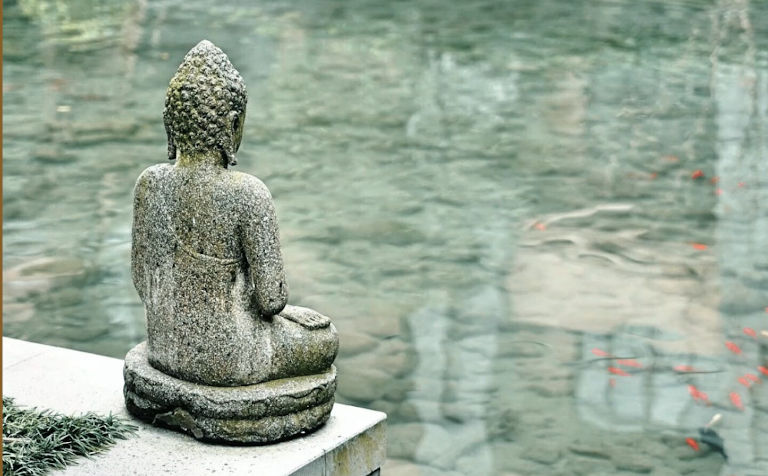 Estàtua de buda practicant mindfulness davant d'un estany