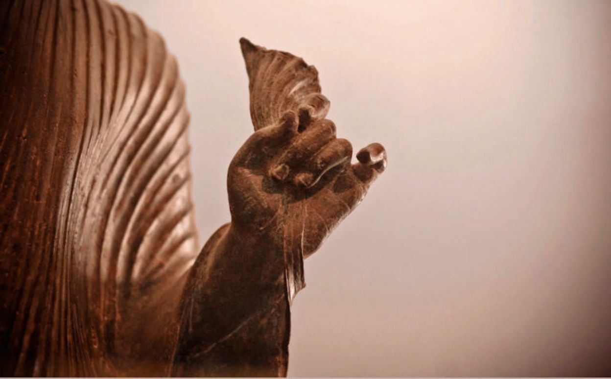 Estatua de bronce representando a Buda haciendo un mudra durante una práctica de meditación.