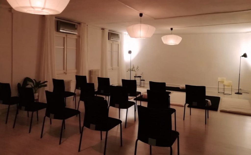 Interior d'una escola de meditació minimalista amb coixins zafú, llum tènue i terra de fusta, llesta per a classe grupal.