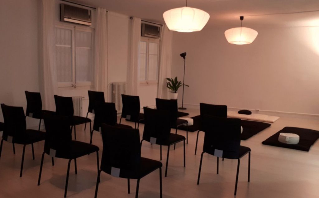 Interior de una escuela de meditación con sillas y futones lista para ofrecer una clase grupal.